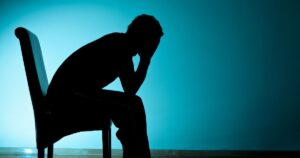 A silhouette of a man sitting on a chair, seemingly depressed | Arimac employee suicide story
