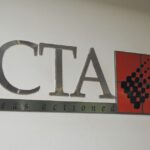 Image of the ICTA logo on a white wall with the tagline "ideas actioned"